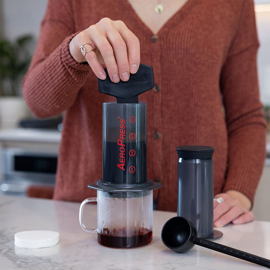 Person using an AeroPress coffee maker to brew coffee
