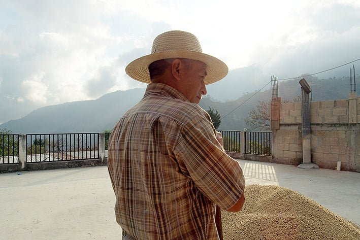 Man in a straw hat standing outdoors with mountains in the background