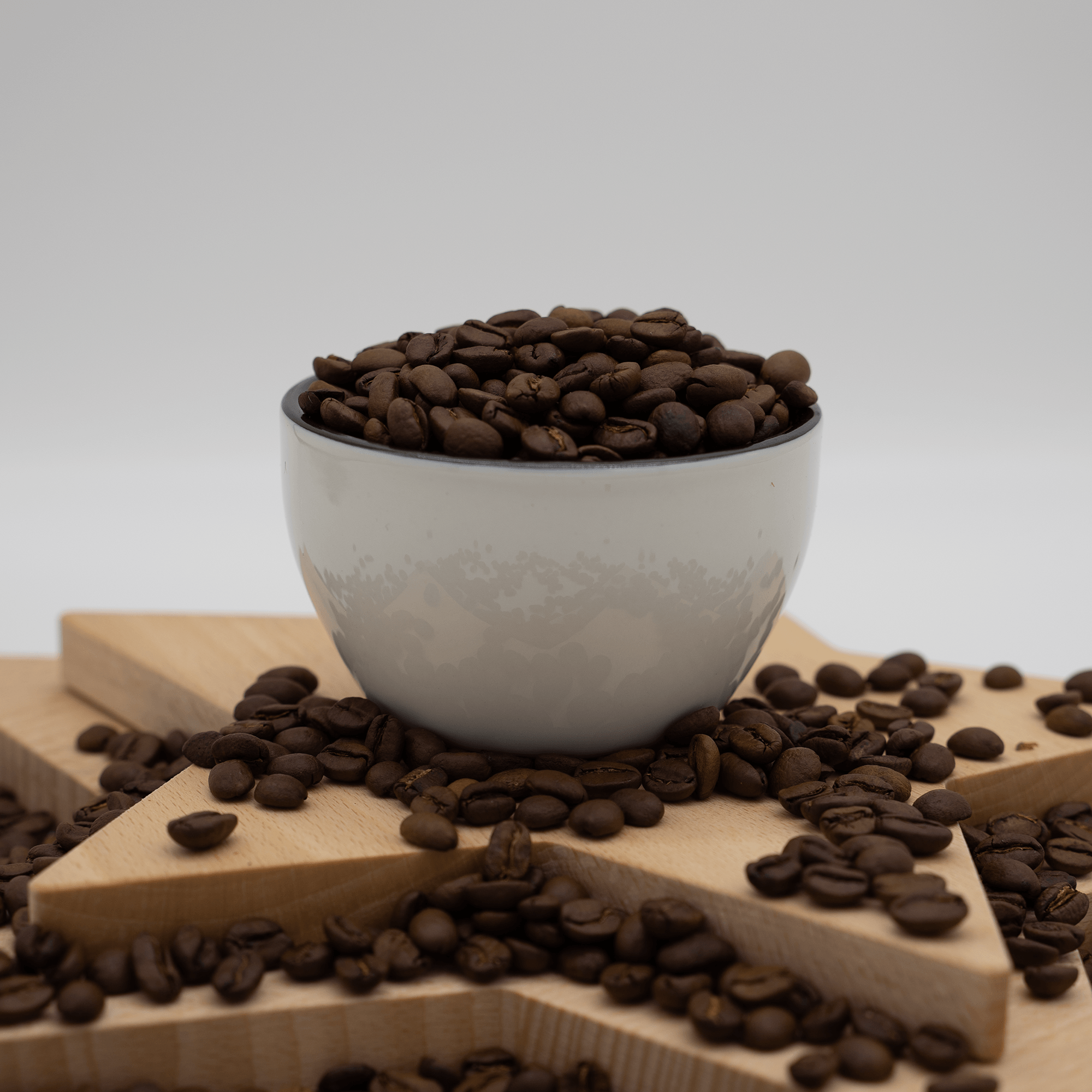 A bowl filled with coffee beans on a wooden surface.