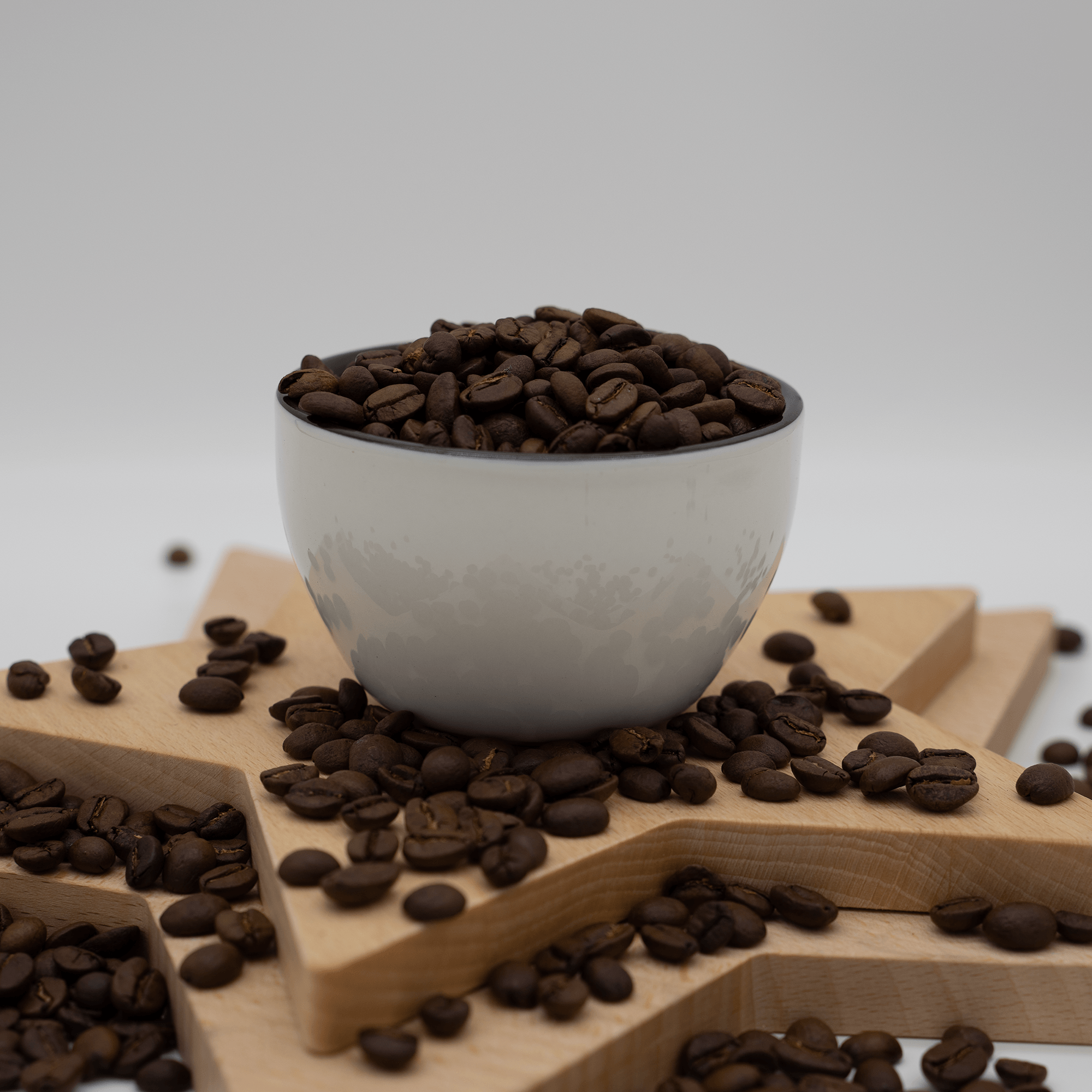 A bowl filled with coffee beans on a wooden star-shaped surface